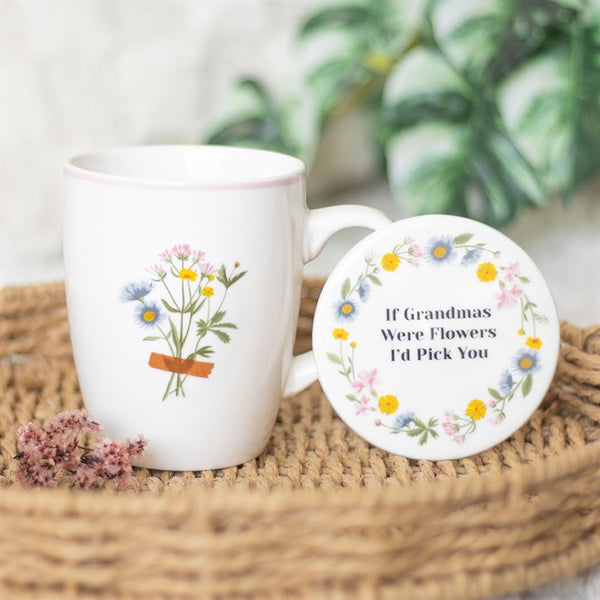 A white ceramic mug with a floral design and a matching coaster that has the text 'If Grandmas Were Flowers, I'd Pick You' on it, placed on a woven surface with a plant background.