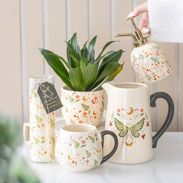 Decorative ceramic pitcher, mug, and plant on a table with a neutral background