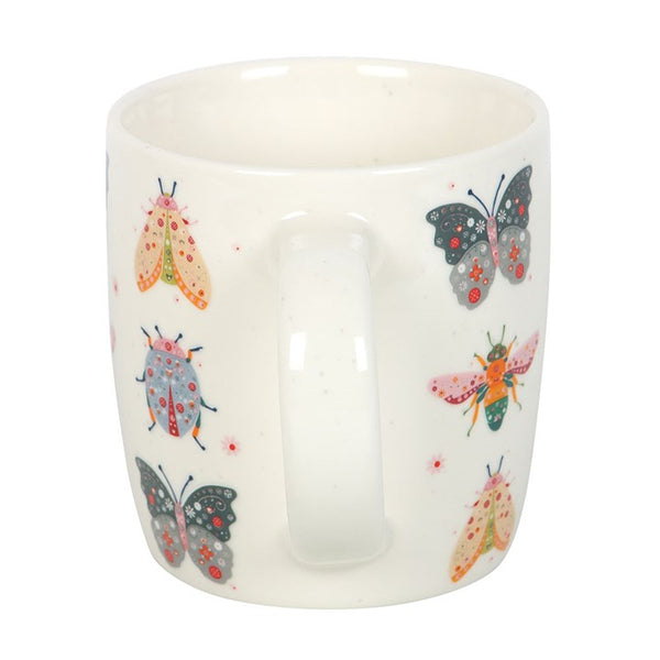 White mug with colorful butterfly and moth design on a white background