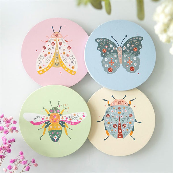 A set of four round coasters with colorful illustrations of a bee, a butterfly, a ladybird, and a moth on a background of pastel colors.