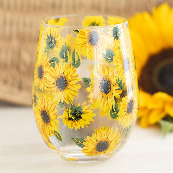 A stemless glass with an all-over sunflower print, with a realistic sunflower in the background.