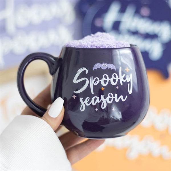 purple mug with 'Spooky season' text held by a hand. Halloween decor