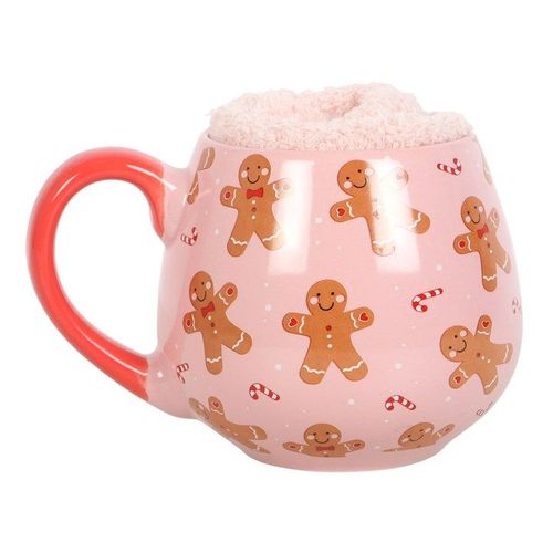 A pink ceramic mug with gingerbread man designs and a red handle, accompanied by a pair of matching socks.