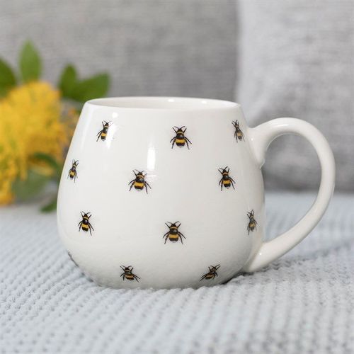 White mug with bumblebee pattern on a textured surface.